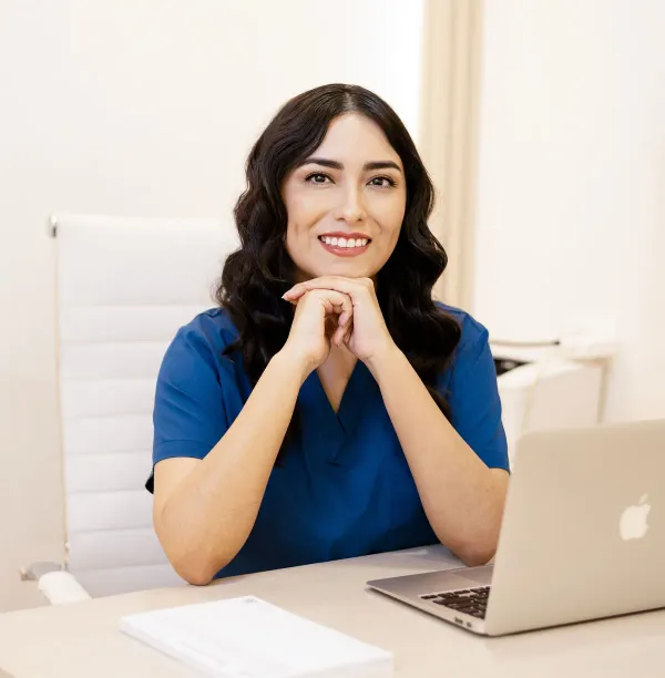 Dra. Estefanía Borges en pijama quirúrgica azul, sentada en su escritorio y escuchando atentamente